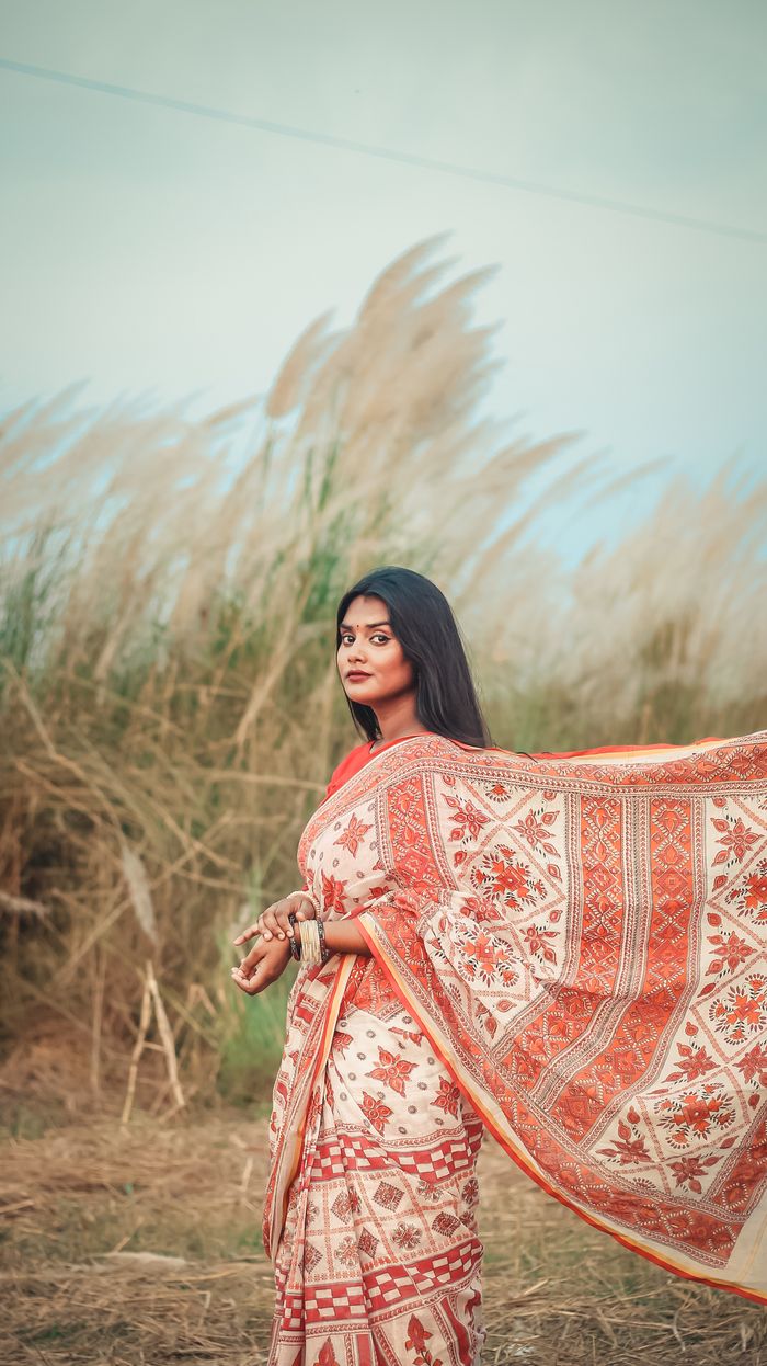 Home Beautiful Indian woman in a traditional saree poses gracefully in a serene outdoor setting, embodying cultural elegance.