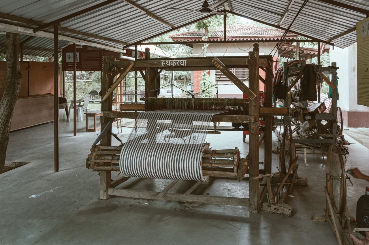 Home A vintage weaving loom on display in an open-air workshop with traditional equipment.