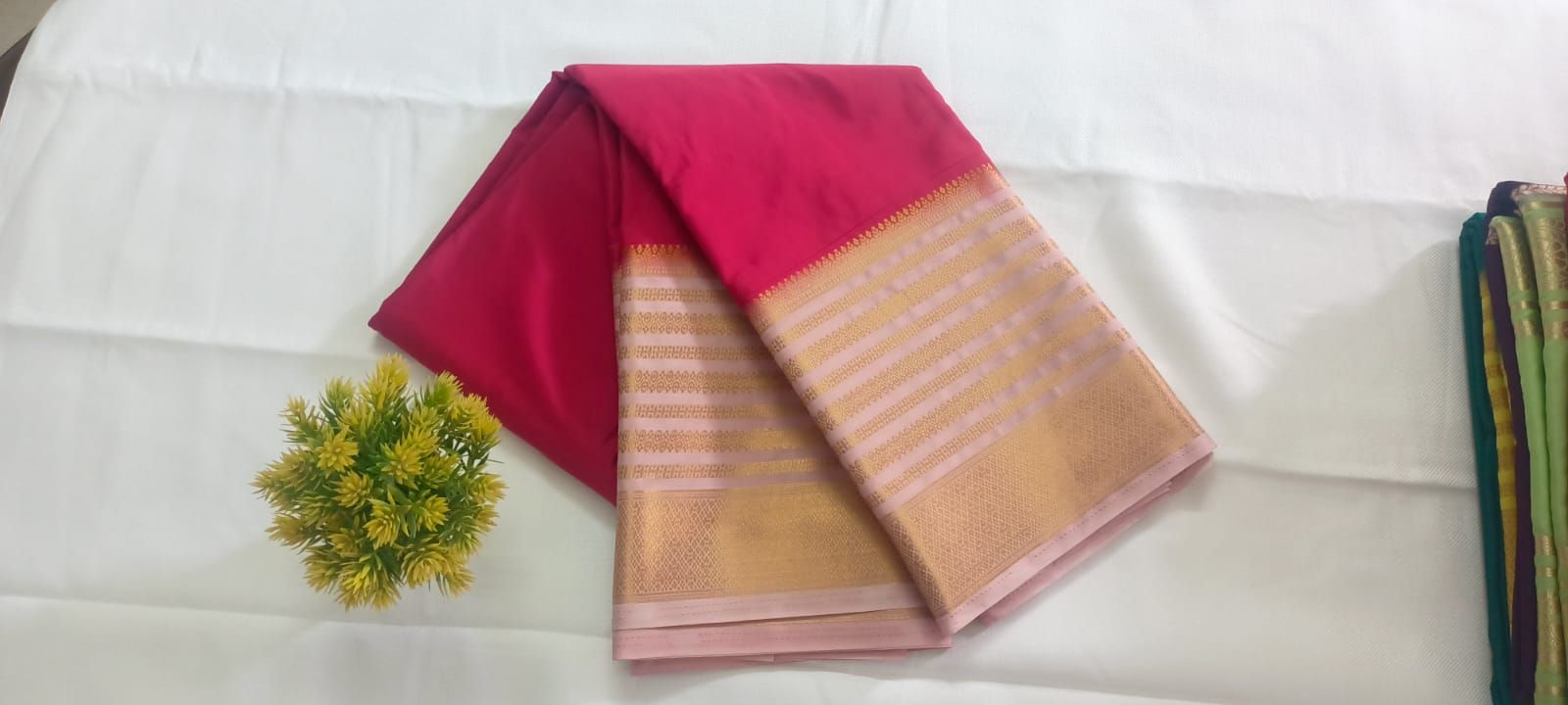 Folded rani pink silk saree with a light pink and gold zari pallu at the Shree Udupu store